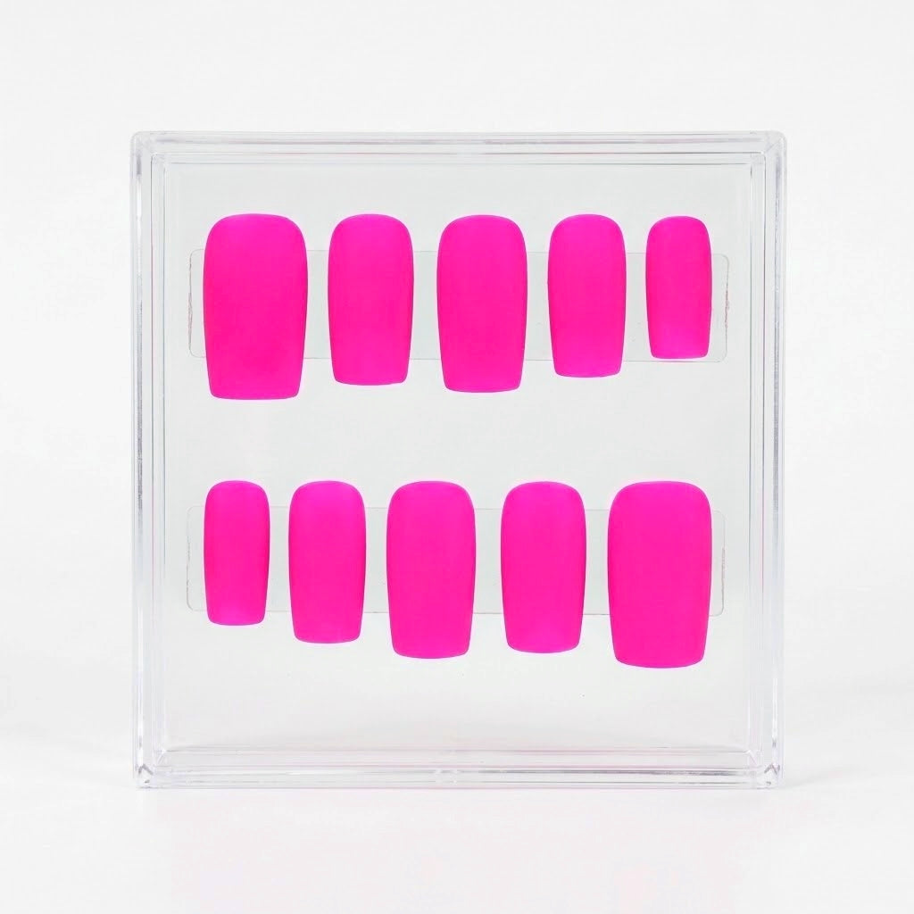 A set of ten neon hot pink press-on nails arranged in two rows inside a clear plastic display box, photographed against a clean white background.