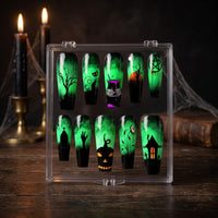 A set of 10 Halloween-themed press-on nails displayed in a clear plastic case on a dark wooden table, with lit candles and spiderwebs in the background.