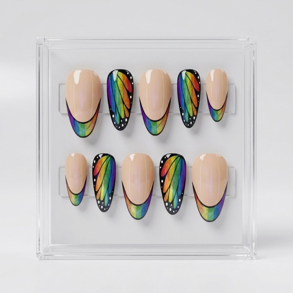 A set of 10 almond press-on nails displayed in a clear acrylic case. The nails feature a split design with a smooth nude-beige half and a black wing-patterned half decorated with a vibrant rainbow gradient.