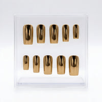 A set of ten metallic chrome gold press-on nails arranged in two rows inside a clear plastic display box on a white background.