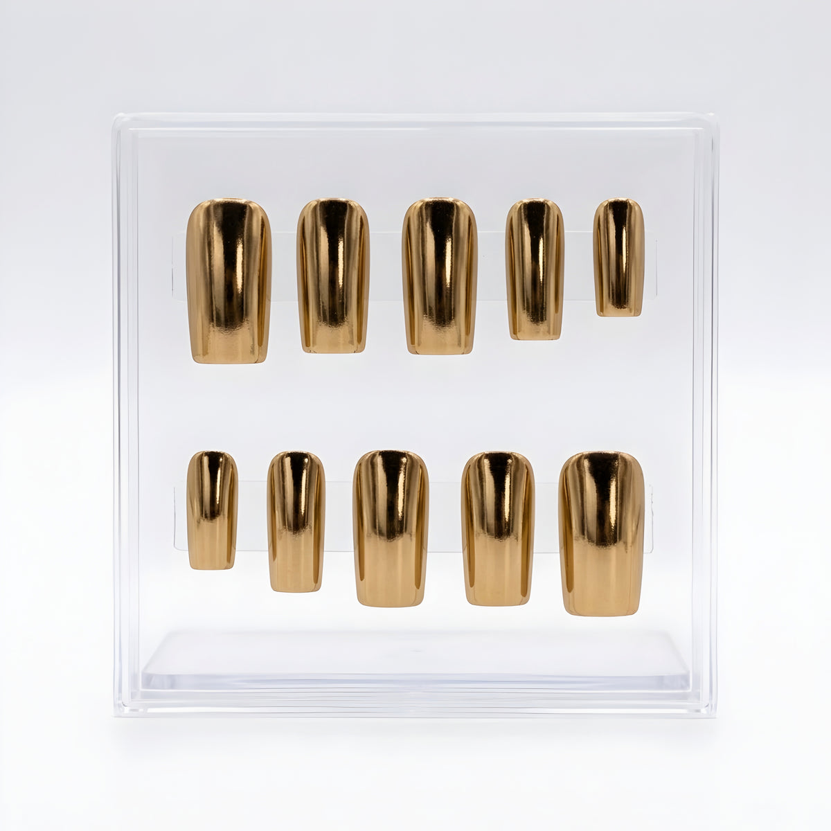 A set of ten metallic chrome gold press-on nails arranged in two rows inside a clear plastic display box on a white background.