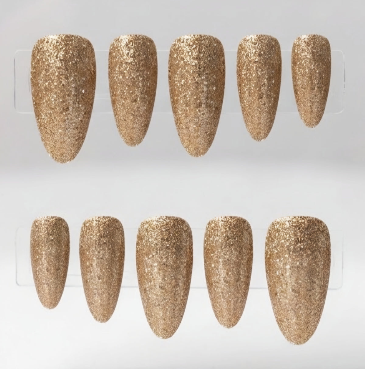 Ten almond-shaped press-on nails with a textured gold glitter finish, arranged in two rows of five on a clear display card against a light gray background.