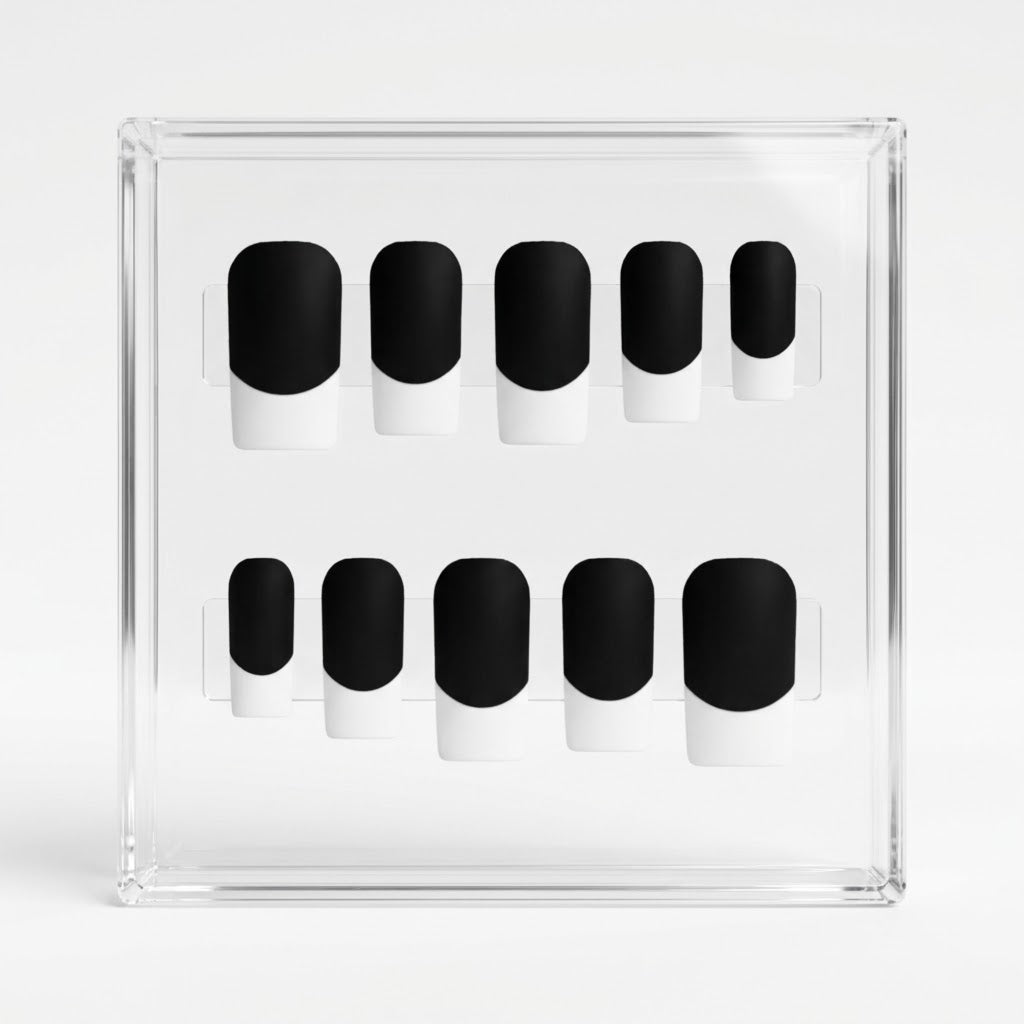 Ten matte black press-on nails with white french tips, arranged in two rows inside a clear acrylic display box on a white background.
