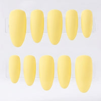 Ten yellow press-on nails arranged in two rows of five on a clear display card against a white background.