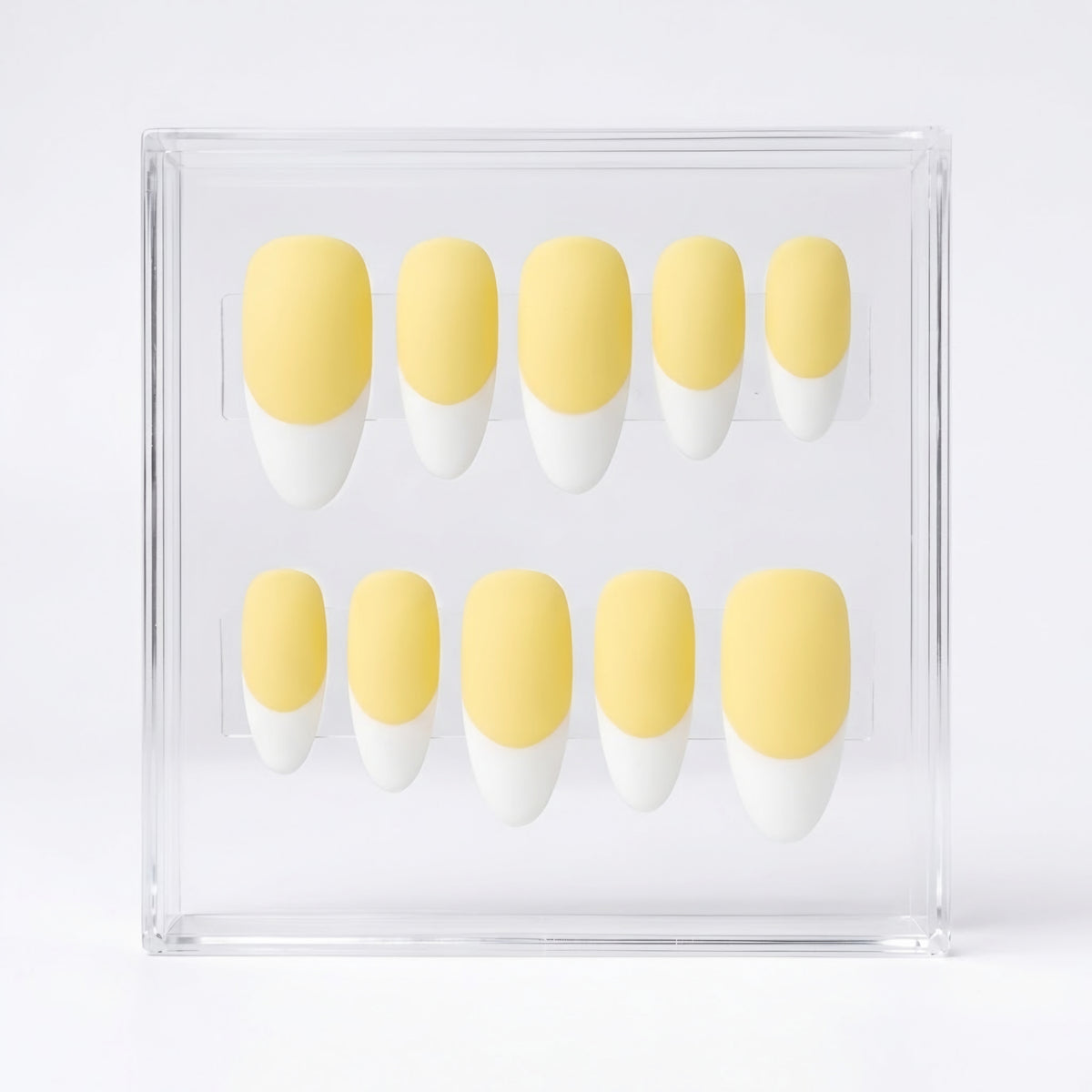 Ten-piece set of false press-on nails with a soft pastel yellow base and white French tips, displayed inside a clear acrylic case on a white background.