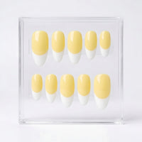 Ten false press-on nails with a pale yellow and white French tip design, displayed in a clear acrylic case against a white background.