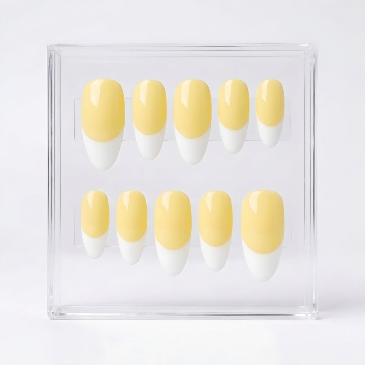 Ten false press-on nails with a pale yellow and white French tip design, displayed in a clear acrylic case against a white background.