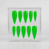 Ten bright neon green stiletto-shaped press-on nails arranged in two rows inside a clear square plastic display box, set against a clean light gray background.