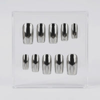 Ten metallic silver chrome press-on nails arranged in two rows inside a clear plastic display box on a light gray background.