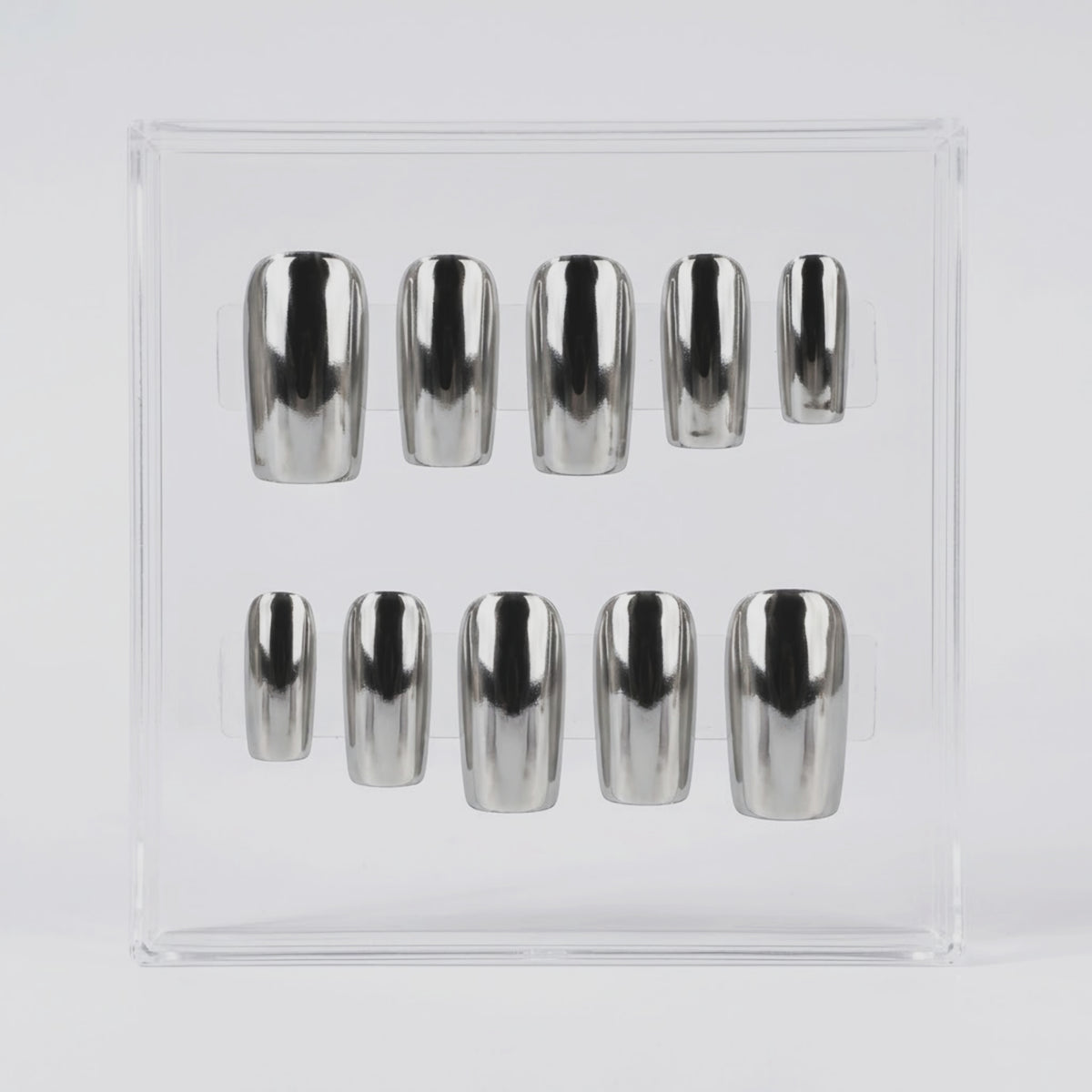 Ten metallic silver chrome press-on nails arranged in two rows inside a clear plastic display box on a light gray background.
