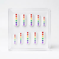 Set of 10 square matte white press on nails with small rainbow hearts running down the centre. Displayed in a  clear display case on a white background.