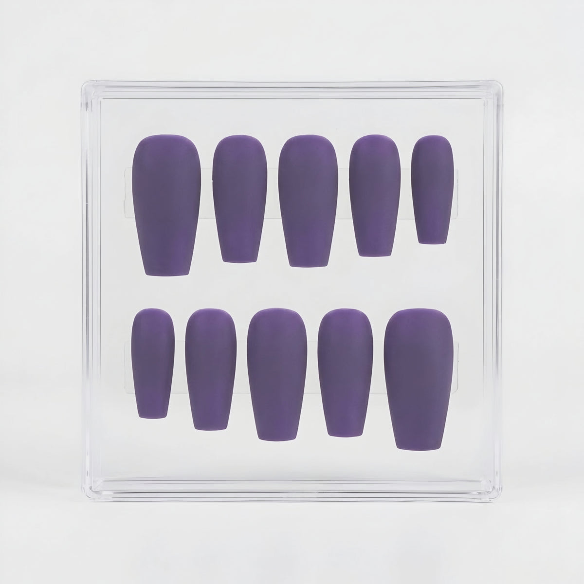 A set of ten matte purple press-on nails arranged in two rows inside a clear plastic display box, photographed against a clean white background.