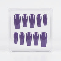 A set of ten glossy purple press-on nails arranged inside a clear plastic display box on a white background.