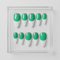 Ten false press-on nails arranged in two rows inside a clear square acrylic tray, featuring a green base and white french tip design on a light gray background.