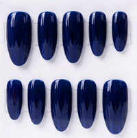 Ten glossy dark blue press-on nails arranged in two rows on a white background.