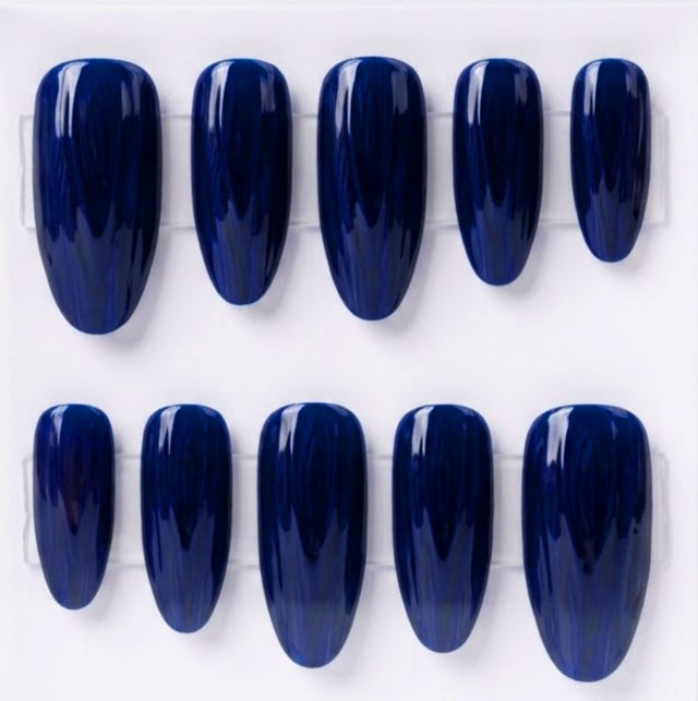 Ten glossy dark blue press-on nails arranged in two rows on a white background.