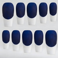 Ten false press-on nails arranged in two rows of five, featuring a dark navy blue base and white French-tips, on a light gray background.