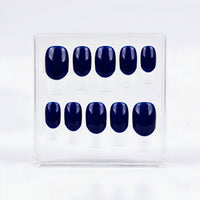 A set of ten press-on nails in a glossy deep navy blue base and white french tips, displayed inside a clear plastic rectangular box on a white background.