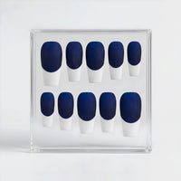 A set of ten press-on nails arranged in a clear plastic display box, featuring a deep navy blue base and white French tips.