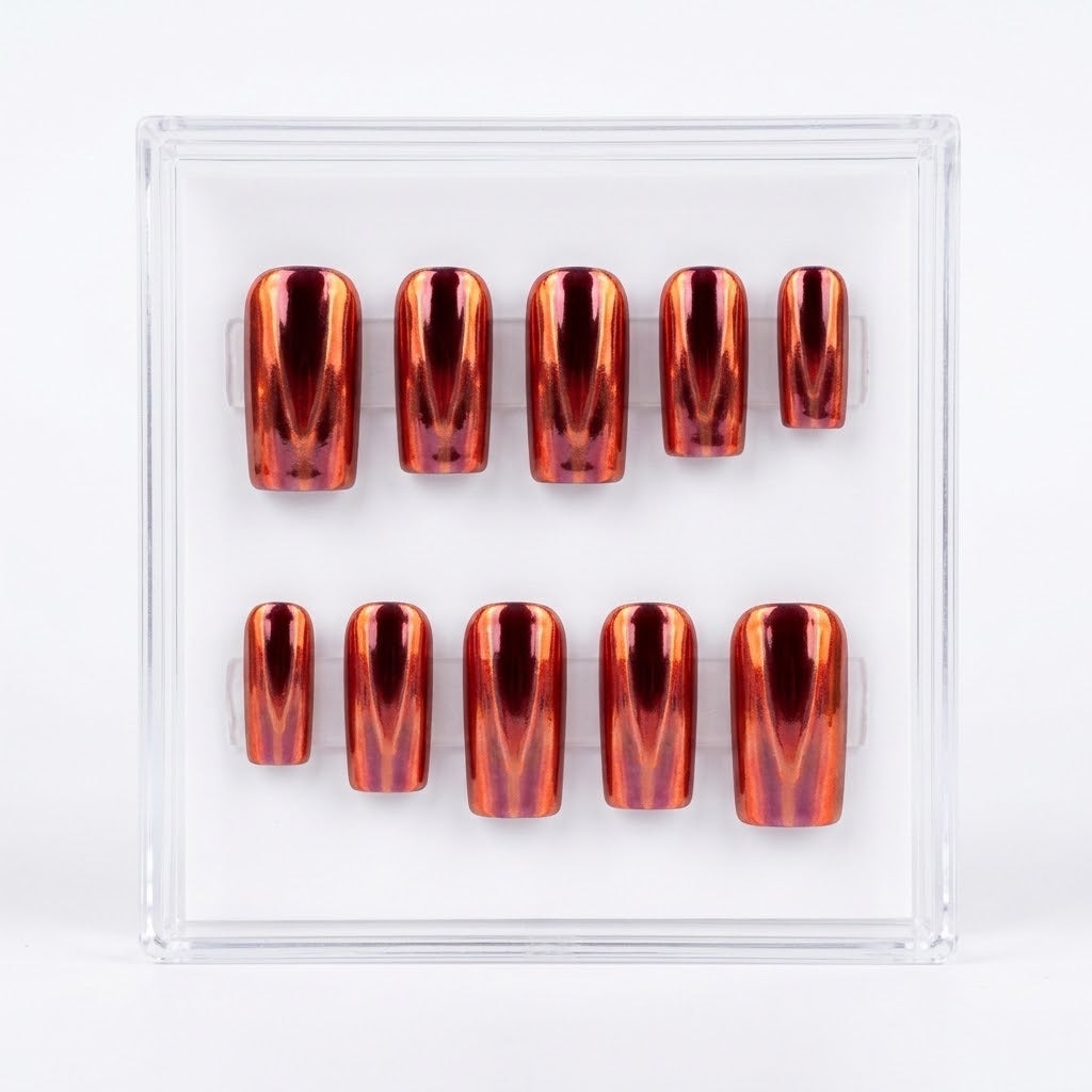 A set of ten metallic chrome oorange/copper press-on nails arranged in two rows inside a clear plastic display box on a white background.