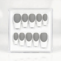 A set of 10 press-on nails in a clear acrylic display case, featuring a classic French manicure with medium gray upper halves and white lower halves.