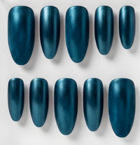 Ten artificial press-on nails in a metallic teal-blue shade, arranged in two rows of five on a light gray background.