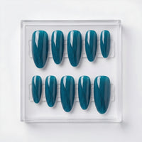 A set of ten press-on nails in a clear plastic display case, featuring a glossy teal and dark blue metallic pattern, shot against a clean white background.