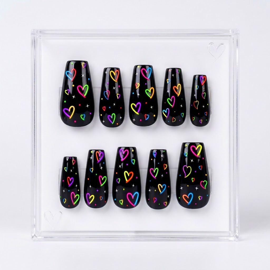 A set of ten glossy black press-on nails with colorful neon heart patterns, displayed inside a clear acrylic case on a white background.