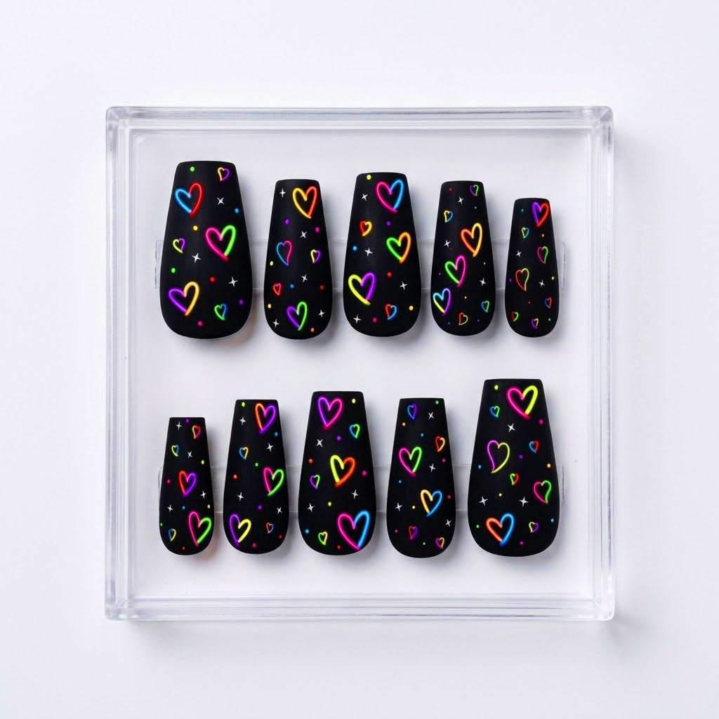 A set of ten ma black press-on nails with colorful neon heart patterns, displayed in a clear acrylic tray on a white background.te