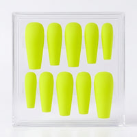 A set of ten bright neon yellow press-on nails displayed inside a clear acrylic storage box on a white background.