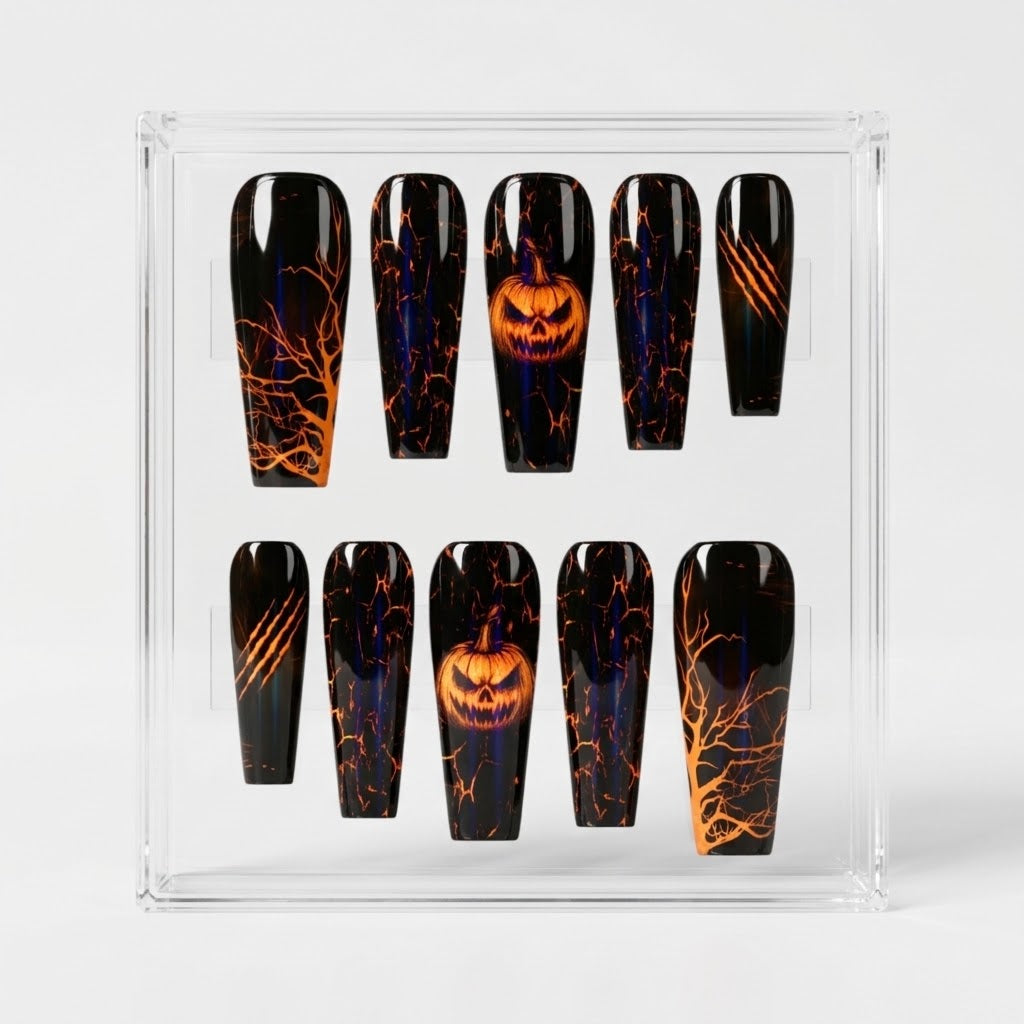 A set of coffin-shaped press-on glossy nails displayed in a clear acrylic case. The nails have a black base with orange and blue Halloween-themed designs, including lightning effects, bare tree branches, claw marks, and jack-o'-lantern faces.