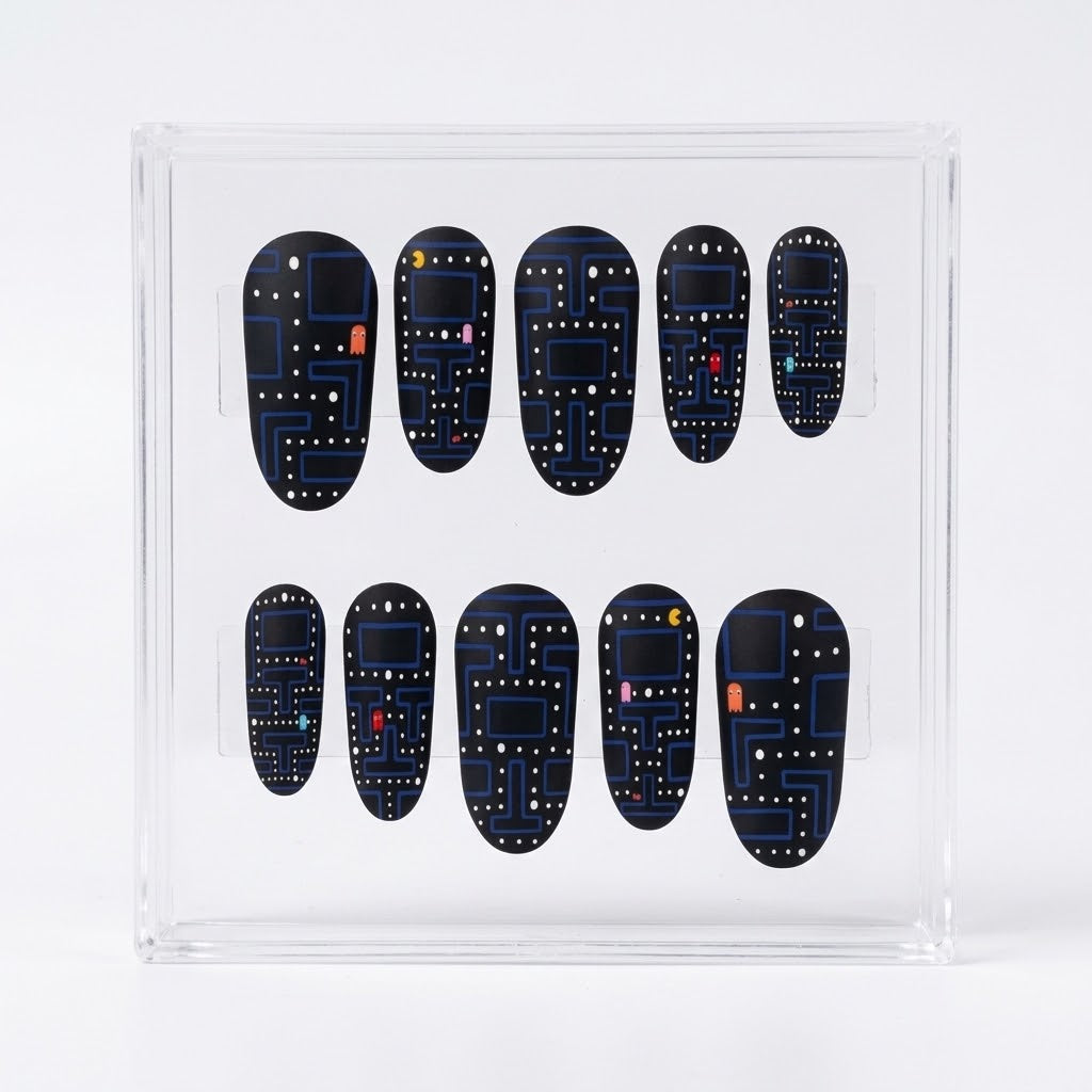 A set of ten matte Pac-man themed press-on nails displayed inside a clear acrylic case, featuring a dark blue and black retro video game maze pattern with small colorful dots.