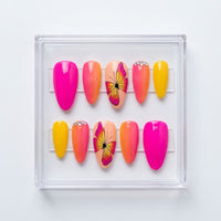 A set of 10 matte almond press-on nails displayed in a clear plastic case on a white background. The nails feature a variety of vibrant colors including hot pink, orange, yellow, and peach, with two central peach nails decorated with a pink and yellow butterfly design and two having small silver rhinestone accents.