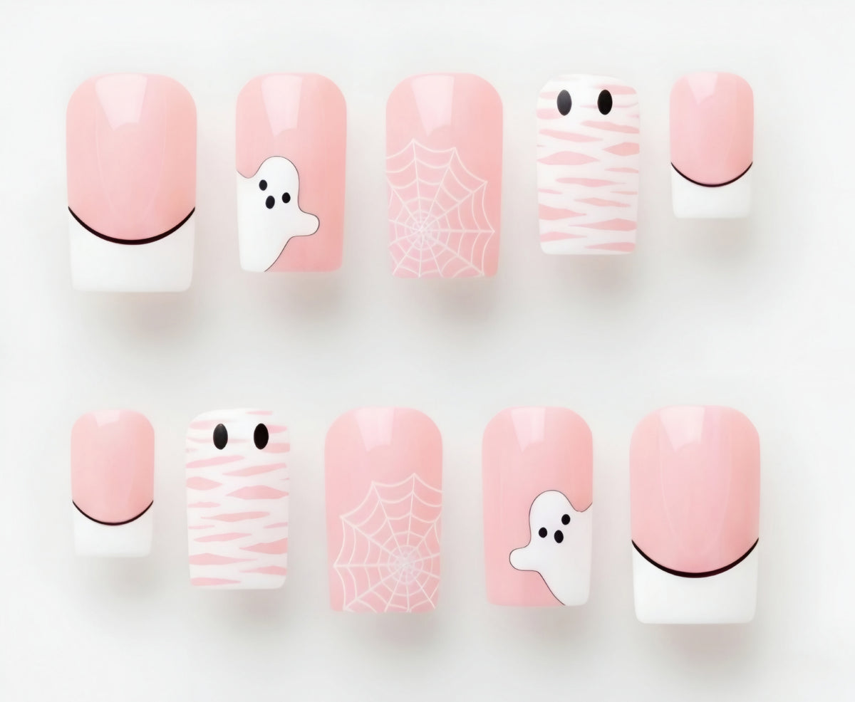 A set of ten pastel pink and white Halloween-themed press-on nails arranged in two rows on a clean white background. The designs include ghosts, spiderwebs, and mummies with black details.