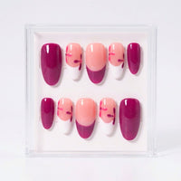 A set of 10 glossy oval press-on nails in a clear acrylic display box, featuring a color palette of deep burgundy, soft peach, and white with small red floral accents.