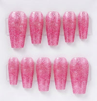 A set of ten pink glitter press-on nails arranged in two rows of five on a clear plastic display card against a white background.
