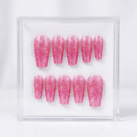 A set of ten glittery pink press-on nails displayed inside a clear acrylic case against a white background.