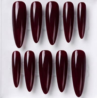 Ten glossy almond-shaped press-on nails in a deep burgundy shade, arranged in two rows on a clear plastic display card against a white background.