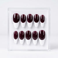 A set of ten false press-on nails displayed in a clear acrylic case against a white background. The nails feature a glossy deep burgundy base and a white  French manicure design.