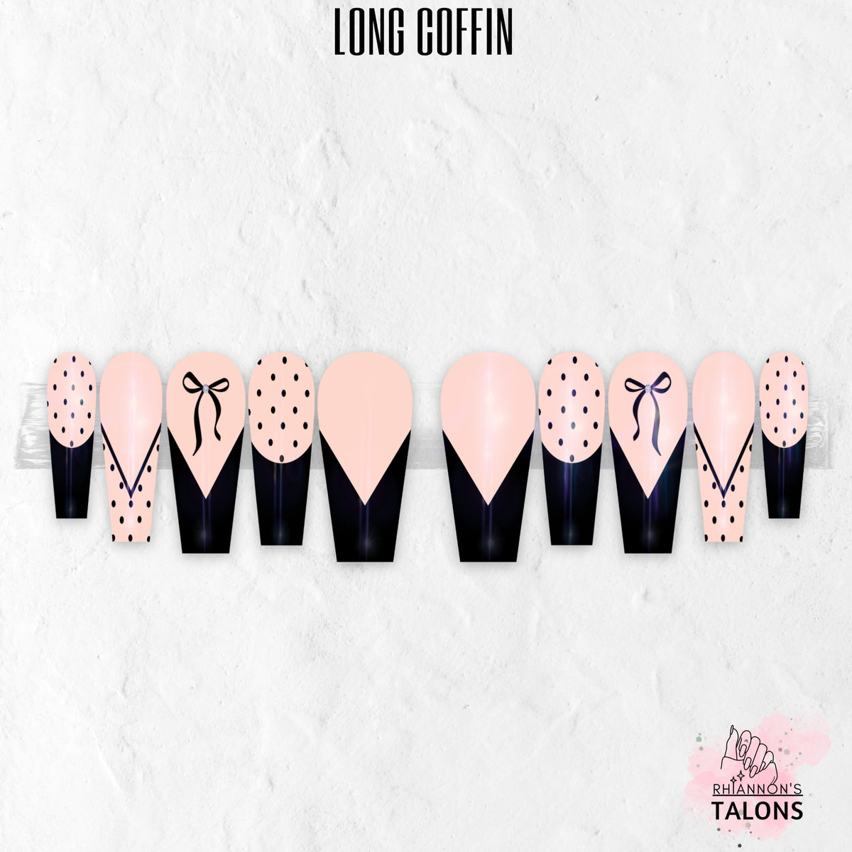 Glossy blush pink and black press-on nails with polka dots, bow nail art, and French tips in long coffin shape.