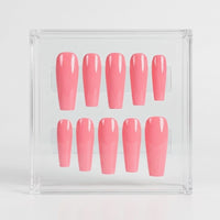 A set of glossy pink press-on nails arranged in two rows inside a clear acrylic display box on a light gray background.