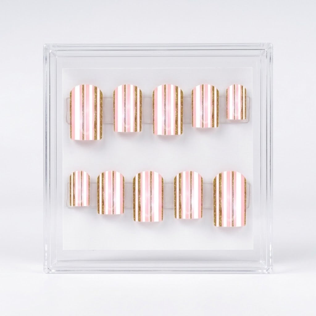 A set of ten square press-on nails with vertical metallic rose gold and gold stripes, displayed inside a clear acrylic case on a white background.