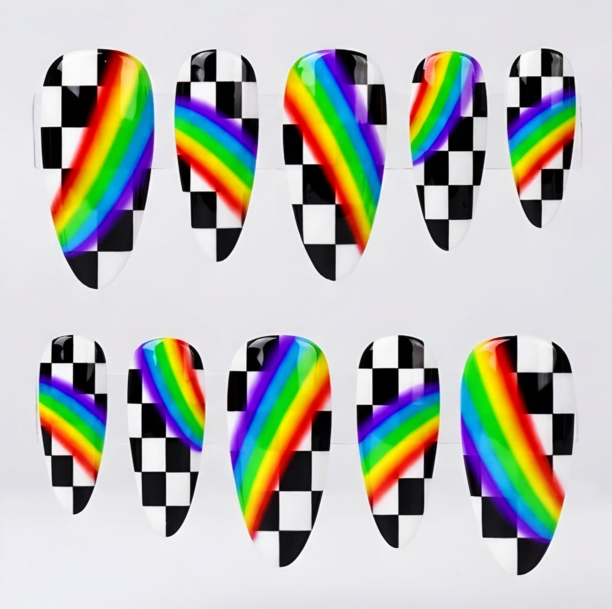 Ten almond press-on nails arranged in two rows of five on a light gray background. Each nail features a glossy black-and-white checkerboard pattern with a diagonal rainbow stripe running through the center.