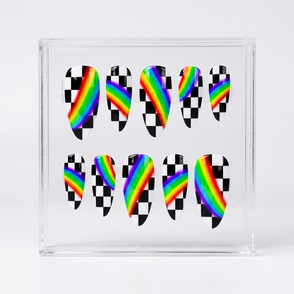 A set of ten almond press-on nails displayed inside a clear square plastic case on a light gray background. The nails feature a split design with a black and white checkered pattern on one half and a vibrant rainbow stripe on the other.