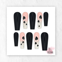Glossy black and pink press-on nail set named Secret Admirer, featuring black nails, blush pink glitter ombré accent nails, and black heart nail art in a long coffin shape.