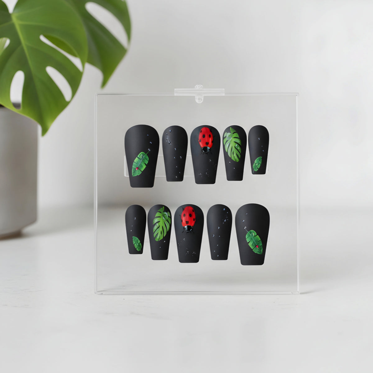 Secret Garden black botanical press-on nails with green leaves and ladybird accents