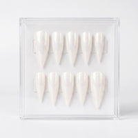Ten stiletto-shaped press-on nails with a shimmering white finish, displayed inside a clear acrylic case on a light gray background.