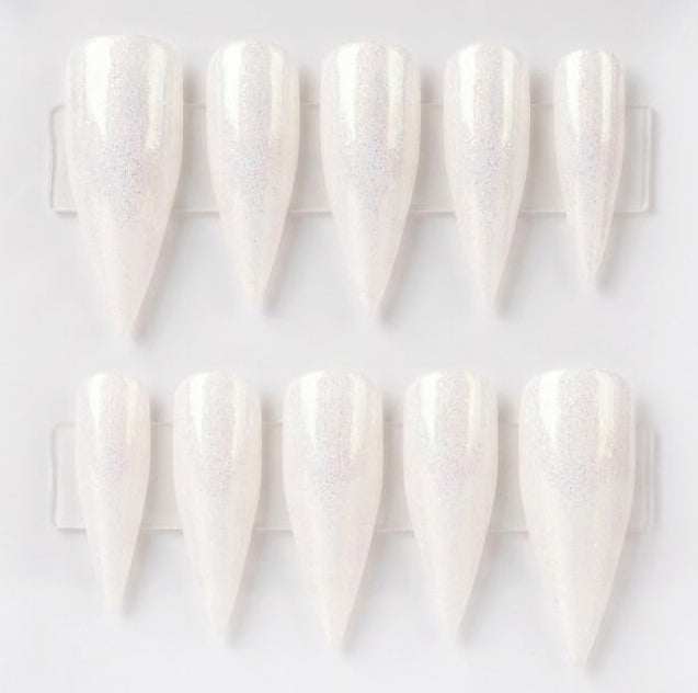 Ten white stiletto press-on nails with a subtle iridescent shimmer, arranged in two rows on a clear plastic display card against a white background.