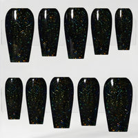 Ten coffin-shaped press-on nails with a glossy black base and dense multicolor iridescent glitter, arranged in two rows on a white background.