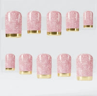 A clear acrylic block displaying 10 square pink glittery press on nails with chrome gold tips, arranged in two rows on a white background.